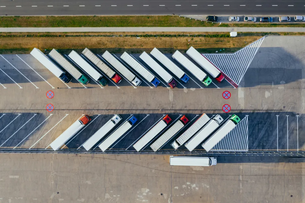 Nákladní automobil parkující s přívěsy s kontejnery obsahujícími materiál CBAM, který potřebuje platformu pro zajištění souladu s CBAM od společnosti Dubrink
